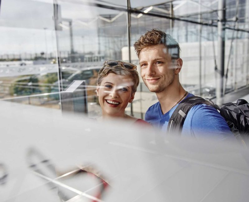 Portrait of smiling couple at the airport looking out of window